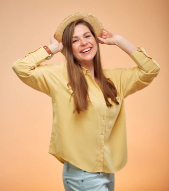 Gülümseyen kadın sarı arka planda izole edilmiş portre. Genç bayan şapkasına dokunuyor.