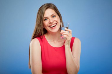 Elinde su bardağı tutan kırmızı elbiseli, gülümseyen kadın. Mavi arka planda izole edilmiş kadın portresi.