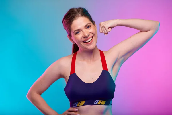 力量肌肉的概念与快乐的运动女性在健身运动服反射她的胳膊 基于霓虹灯彩色背景的女性健身肖像 — 图库照片