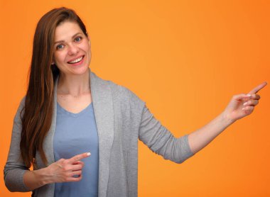 İzole edilmiş turuncu arkaplandaki fotokopi alanını gösteren mutlu kadın mavi gömlekli genç mutlu bayan..