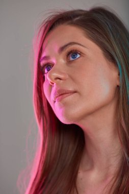 Genç bir kadın yukarı bakıyor, kadın yüzü çok renkli bir ışıkla güzellik portresi. Doğal ten ve uzun saç..