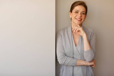 Gülümseyen kadın kopya alanı olan duvarın yanında duruyor..