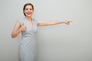 Kısa saç stili olan genç bir iş kadını parmağını kaldırır ve parmağını kaldırmaz. Ayrı bir kadın stüdyo resmi. Gri elbiseli genç bir iş kadını..