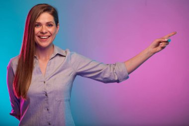 Parmakla işaret eden gülümseyen kadın, neon ışıklı portre renk efekti. Kadın modeli neon arkaplanda izole edildi