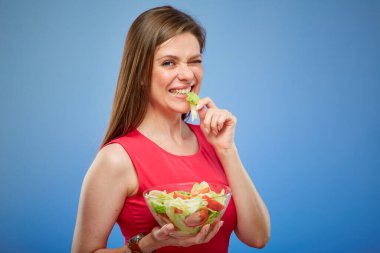 Kırmızılı gülümseyen genç bayan elleriyle yeşil salata yiyor..