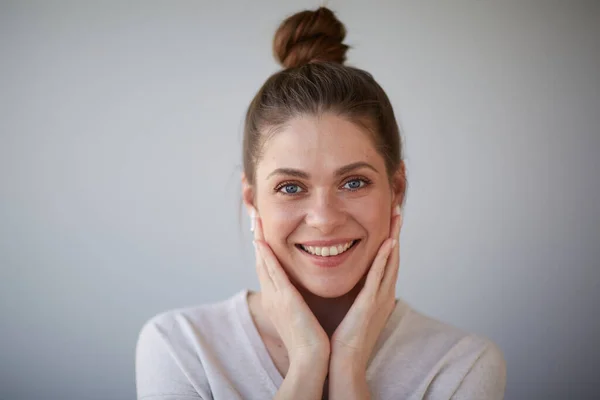 Smiling happy woman with bunch haircut touching face. Female head shot with shallow depth of field.