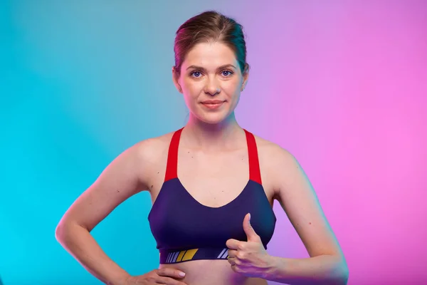 穿着运动胸罩的胖女人戴着大拇指 女性健身肖像孤立在霓虹灯的色彩背景上 瑜伽教师的健康生活方式概念 — 图库照片