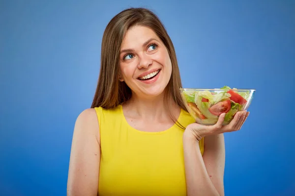 女人笑着 把绿色沙拉放在玻璃碗里 蓝色背景的孤立的女性肖像 — 图库照片