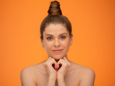 Çıplak omuzlu gülümseyen bir kadın yüzünü ellere yaslar, güzellik tarzında izole edilmiş bir portre, doğal bir yüz portresi, rötuş yapmadan..