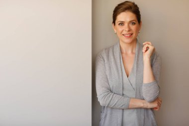 Gülümseyen kadın kopya alanı olan duvarın yanında duruyor..