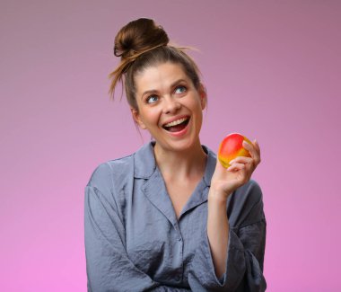 Gülümseyen kadın pijaması elmalı ve yukarı bakıyor, pembe kadın portresi üzerinde soyutlanmış.