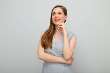 Gülümseyen kadın yüzüne dokunuyor ve başka tarafa bakıyor, gri iş elbisesi izole edilmiş portre..