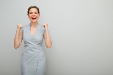 Bu başarıdır. Genç iş kadını kollarını büker, izole edilmiş kadın stüdyo resmi, gri elbiseli genç iş kadını..