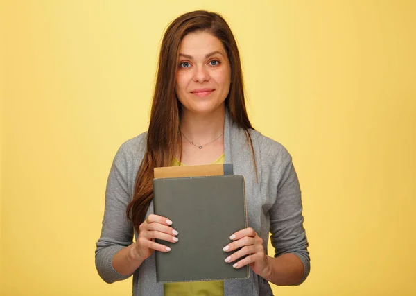 Smiling woman teacher or student holding books. isolated female portrait on yellow background. Smiling  girl with long hair.