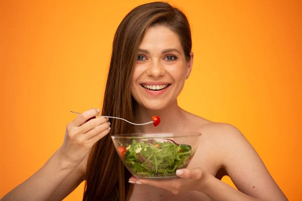 オレンジ色の黄色の背景に緑のサラダ孤立した肖像画を食べる裸の肩を持つ女性 — ストック写真