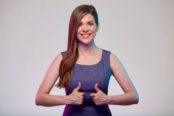 Улыбающаяся деловая женщина показывает большие пальцы вверх. Женщина бизнесмен с длинными волосами в сером платье изолированный портрет.