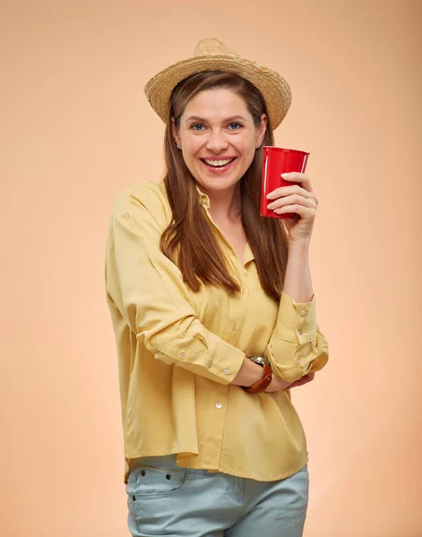 黄色の背景に女性の隔離された肖像画 笑顔女性でわら帽子保持赤コーヒーカップ — ストック写真