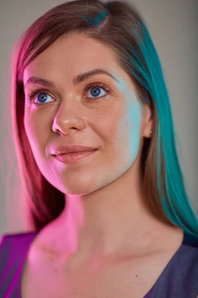 young woman looking away, female face beauty portrait with multicolored light. futuristic look girl natural skin and long hair.