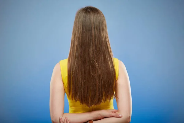 黄色のカジュアルなドレスの女性が長い髪で後ろに立っている 青い背景の孤立した女性の肖像画 — ストック写真