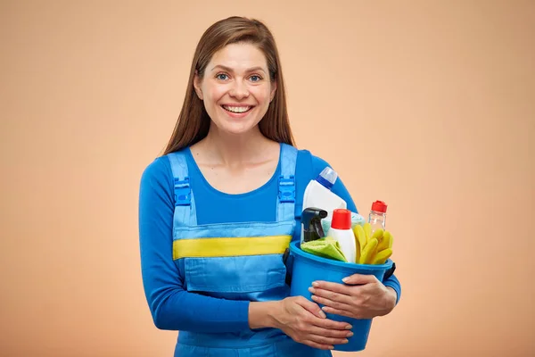 Happy woman in overalls with cleaning products. isolated portrait on brown beige background.