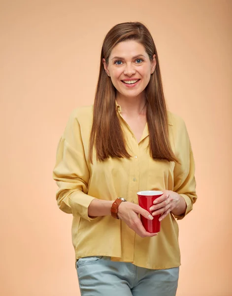 Happy woman isolated portrait on yellow background. Young lady with long hair holding red coffee cup.