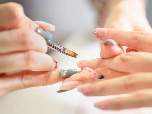 ネイルニスで女性の爪をカバーする女性美容師のクローズアップ — ストック写真