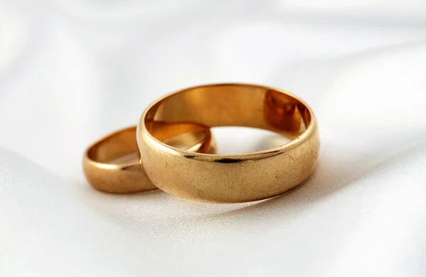 Golden wedding rings on white silk — Stock Photo, Image
