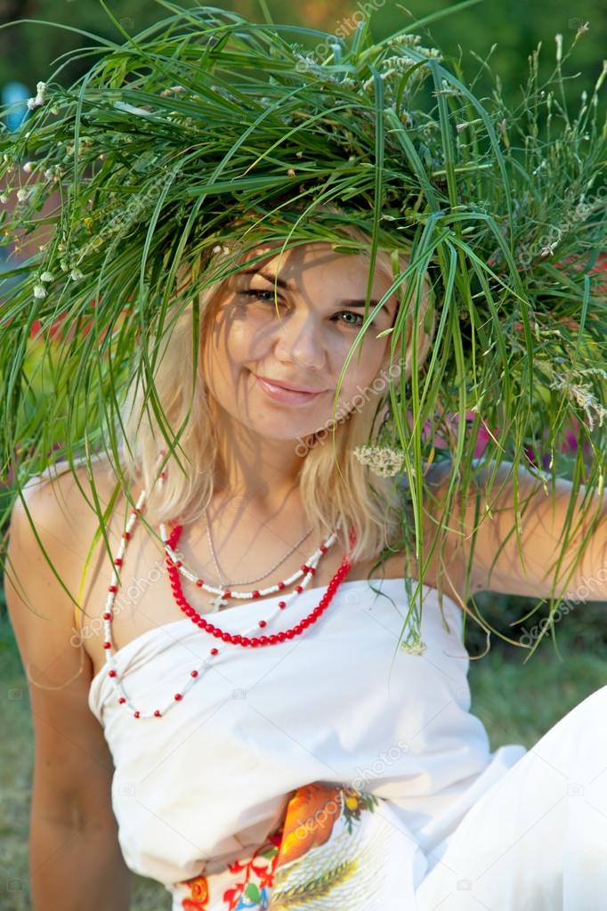 A beautiful woman wearing a crown of grass and Slavic costume.