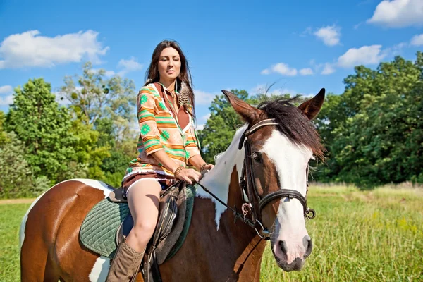 Молодая девушка в костюме индейца едет на красной лошади — стоковое фото