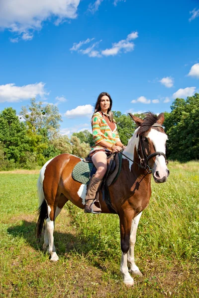 Молодая девушка в костюме индейца едет на красной лошади — стоковое фото