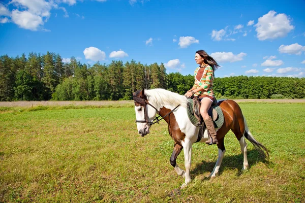 Uma jovem vestida como um índio monta um cavalo de pintura — Fotografia de Stock