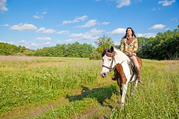 Uma jovem vestida como um índio monta um cavalo de pintura — Fotografia de Stock