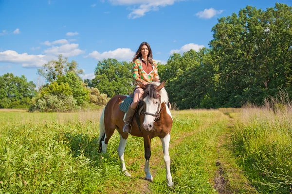 Una joven vestida de india monta un caballo de pintura — Foto de Stock