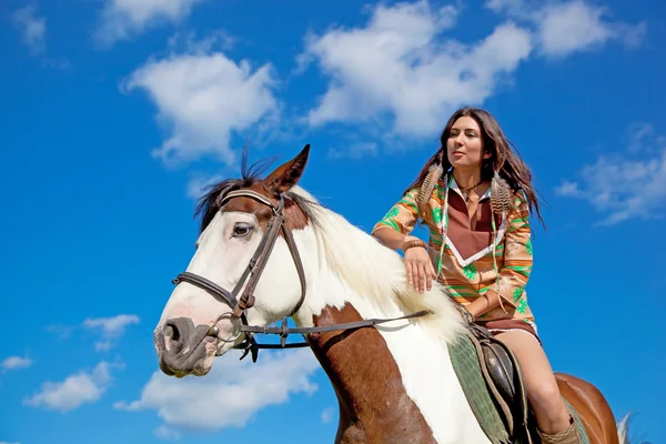 Uma jovem vestida de índia monta um cavalo de pintura. Foco em — Fotografia de Stock