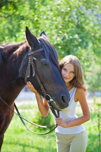 Ung flicka med en häst i trädgården. — Stockfoto