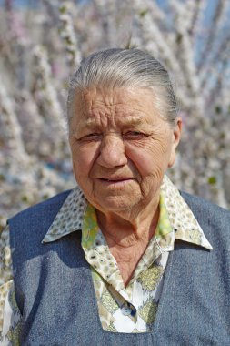 çiçekli garde arka plan üzerinde gülümseyen yaşlı kadın