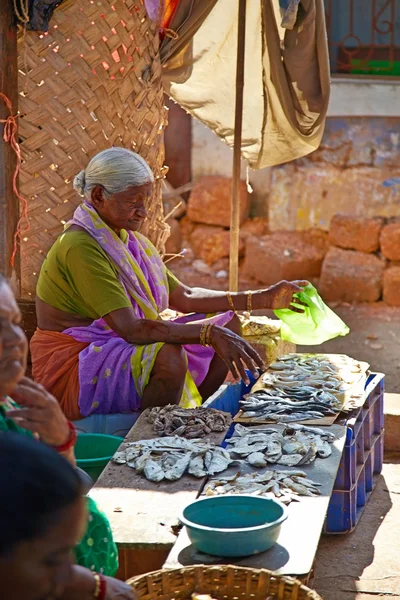 Siolim, goa, Indie - cca prosince 2013: starší žena prodává — Stock fotografie