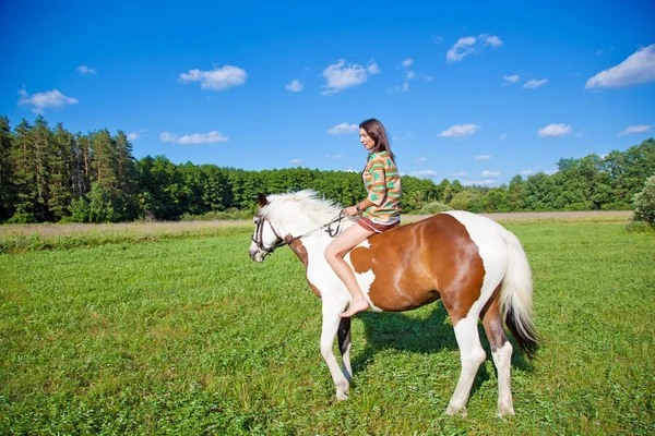 Uma jovem vestida como um índio monta um cavalo de pintura — Fotografia de Stock