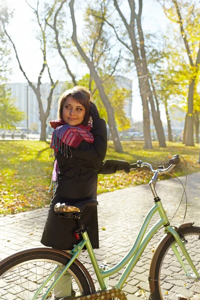 Jeune belle fille marchant dans le parc d'automne sur un vélo — Photo