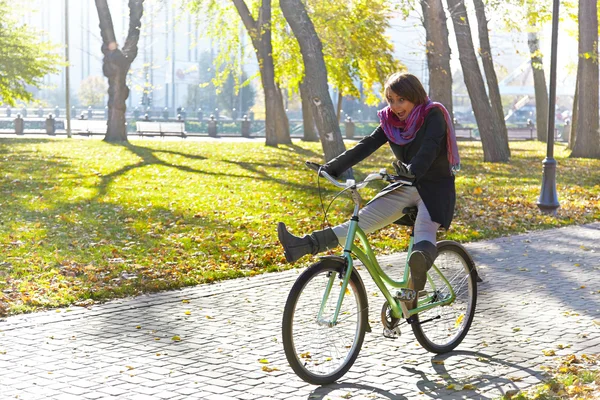Una joven aprende a andar en bicicleta en el parque de otoño. Retroiluminación . —  Fotos de Stock