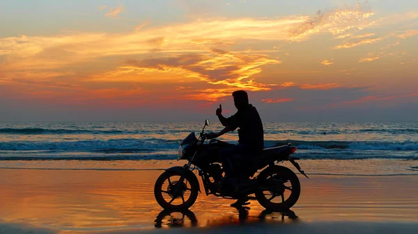 Motocyklista na zachód słońca na plaży. — Zdjęcie stockowe