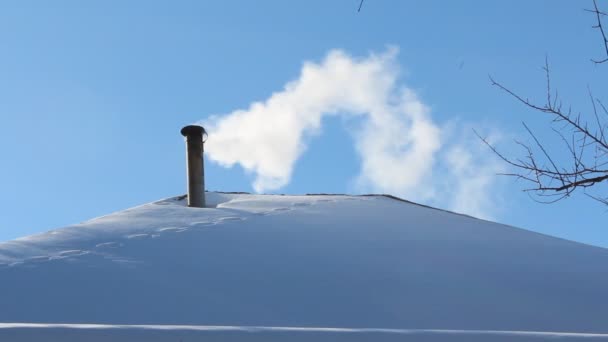 Крыша дома со снегом и белым дымом из дымохода — стоковое видео