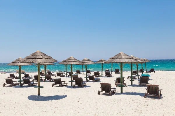 Liegestühle und Sonnenschirme am sonnigen Strand — Stockfoto