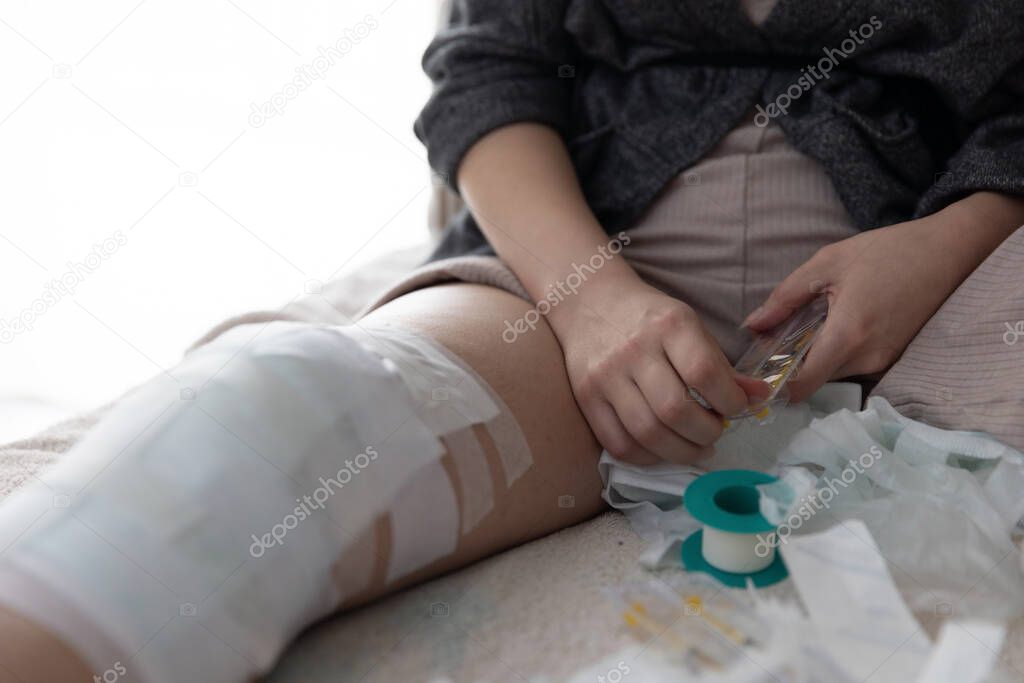 Close up shot with a young woman getting ready to take her injection, after an ACL surgery.