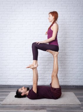Genç çift evde farklı yerlerde akro yoga pozları vererek eğleniyor..