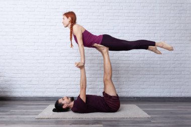 Genç çift evde farklı yerlerde akro yoga pozları vererek eğleniyor..