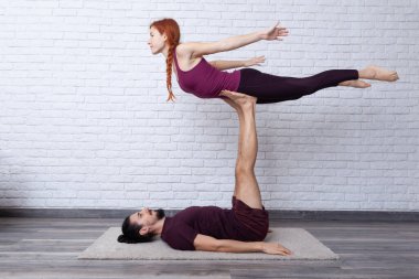 Genç çift evde farklı yerlerde akro yoga pozları vererek eğleniyor..