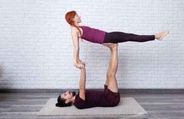 Genç çift evde farklı yerlerde akro yoga pozları vererek eğleniyor..