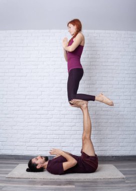Genç çift evde farklı yerlerde akro yoga pozları vererek eğleniyor..