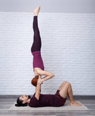 Genç çift evde farklı yerlerde akro yoga pozları vererek eğleniyor..